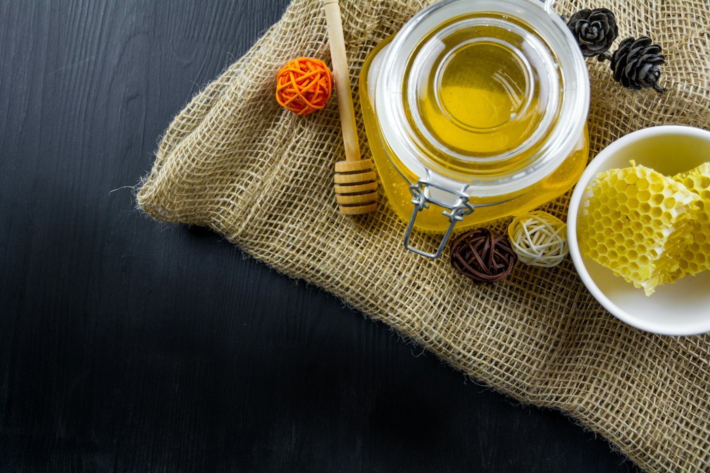 Golden honey in a glass jar with a wooden dipper.