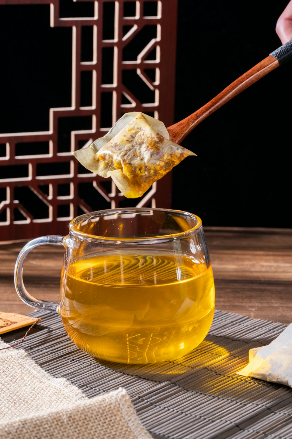 Hand holding tea bag over mug of hot tea.