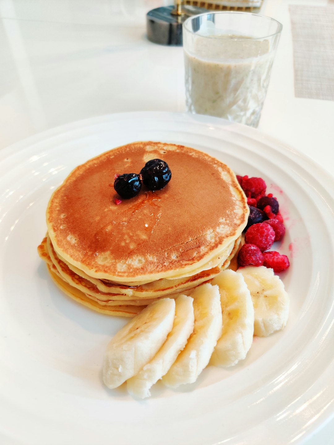 Golden pancakes with blueberries, syrup, bananas, and raspberries.